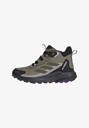 Chaussure de randonnée montante vert olive avec des accents noirs et gris, semelle noire, lacets, languettes et logo TERREX sur le côté.
