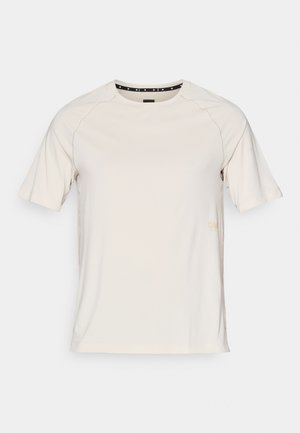 Kortermet kremfarget t-skjorte i glatt stoff, med rund halslinning og subtilt merke i gull på venstre side.