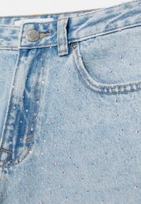 Lyseblåt denimstof med forlomme, bæltestrop, knaplukning og små spredte flerfarvede rhinsten.