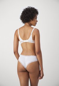 Witte bh met kant en bijpassende slip, voorzien van verstelbare bandjes, bloemenkantaccenten en een gladde stofstructuur.