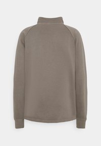 Suéter tipo pullover en un suave tejido gris, con un cuello alto, mangas largas tipo raglán y puños acanalados. Textura suave con costuras mínimas.