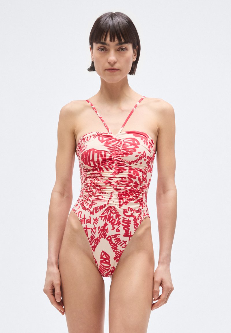 Bañador de una pieza rojo y beige con cuerpo ajustado, detalles de fruncidos y tirantes delgados ajustables con un estampado estilo grafiti.