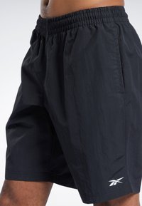 Mustad mustadest sport shorts, mis on valmistatud kergest kangast, elastse vöökohtaga ja väikese valge logoga alumises vasakus nurgas.