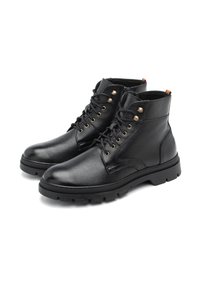 Zwarte leren enkelboots met een gestructureerde afwerking, ronde neus en metalen oogjes. Voorzien van een dikke loopzool en een gevoerde kraag voor extra steun.