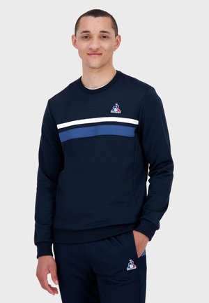 Navy sweatshirt with a crew neck, featuring white and blue horizontal stripes across the chest and a small logo on the left side.