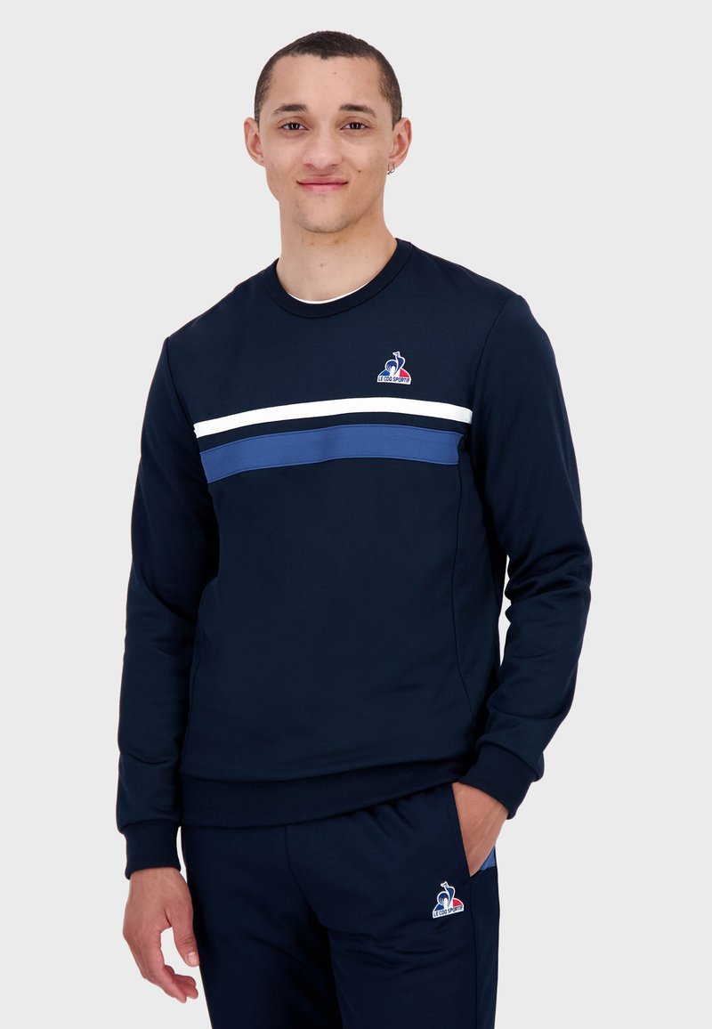Felpa navy con collo a giro, caratterizzata da righe orizzontali bianche e blu sul petto e da un piccolo logo sul lato sinistro.