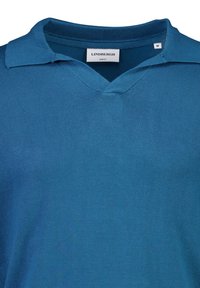 Niebieska polówka z krótkim rękawem, wykonana z dzianiny, z dekoltem w serek i kołnierzykiem. Metka informuje o marce "LINDBERGH" oraz rozmiarze "M".