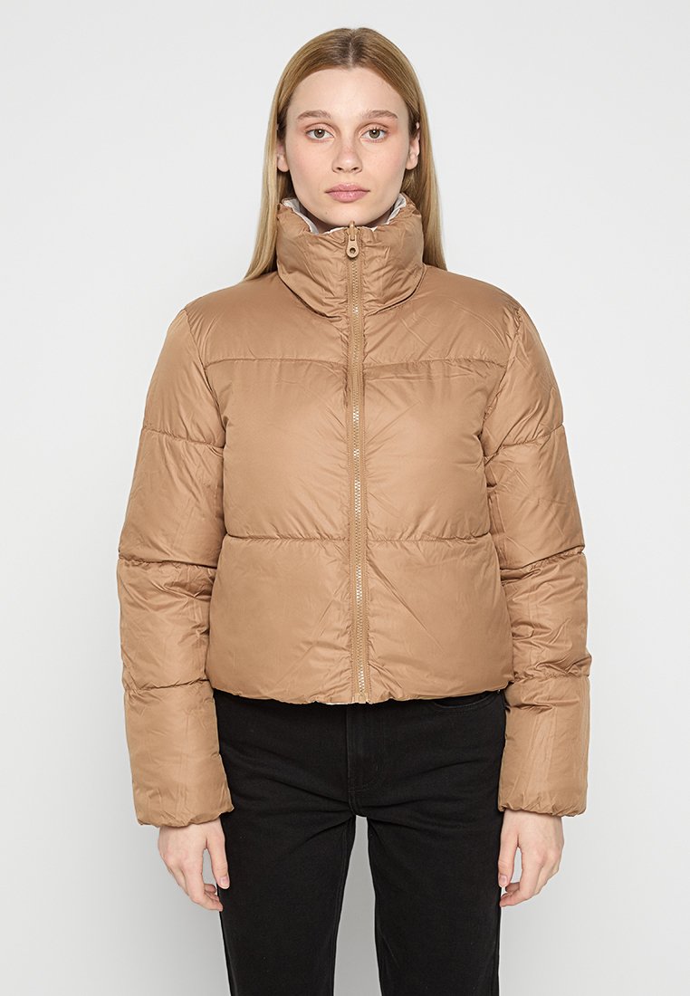 Chaqueta de abrigo corta marrón con un alto cuello, que presenta un cierre en la parte delantera y un diseño acolchado. El tejido tiene un acabado suave y brillante.