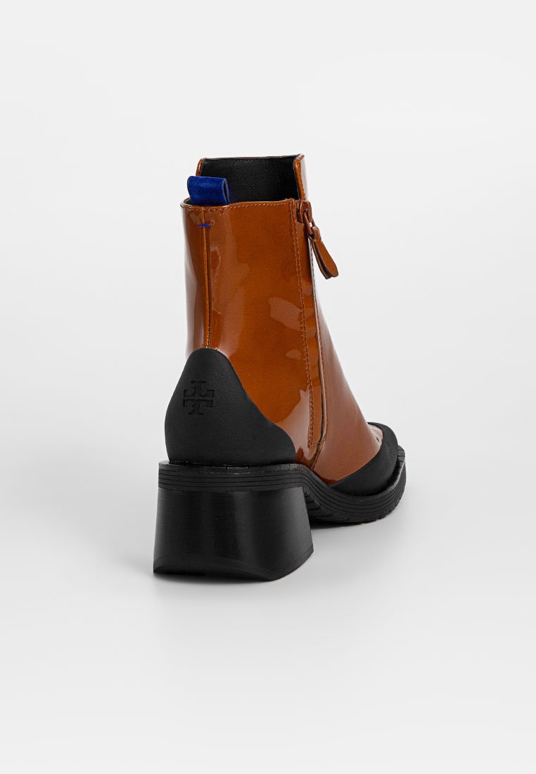 Braune Lackleder-Ankle Boots mit schwarzem Absatz und rundem Zehenbereich. Mit einem seitlichen Reißverschluss und blauen Akzenten an der Oberkante. Texturiertes Absatzdetail.