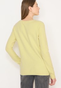 Maglione giallo chiaro realizzato in materiale morbido. Presenta una scollatura a girocollo, maniche lunghe e polsini e orlo a coste. Vestibilità classica, design posteriore senza cuciture.
