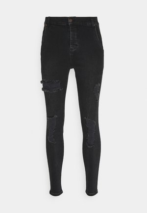 Jeans skinny negros de mezcla de denim con áreas desgastadas y bordes deshilachados en las rodillas. Presenta un diseño clásico de cinco bolsillos y cierre frontal con botón.
