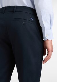 Mornarske hlače iz lahkega materiala imajo zadnji žep z gumbom in majhen vezen pesji logotip nad žepom.
