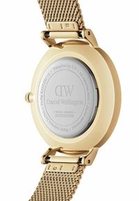 Montre en acier inoxydable doré avec un bracelet en maille. Le dos présente un logo gravé et un numéro de série, avec une surface lisse et réfléchissante.