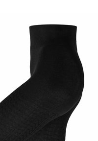 Calzino nero alla caviglia con bordo a costine, texture liscia e un motivo sottile lungo il lato. Adatto per abbigliamento casual o formale.