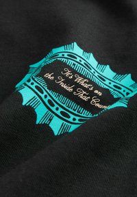 Tela negra con un gráfico turquesa y un borde decorativo. El texto central dice "Lo que importa es lo de dentro". La textura es suave.