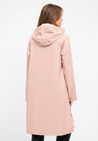 Rosa vattentät jacka med huva, långa ärmar och sidodragkedjor. Slät textur med en rak silhuett som når mitt på låret.