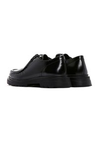 Zapatos de cuero negros con puntera redondeada, diseño de cordones y suelas de goma gruesa con dibujo para mayor tracción. Superficie suave y brillante.