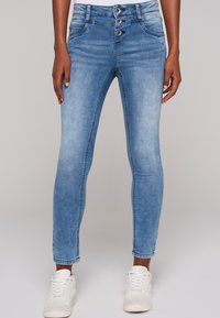 Vaqueros de mezclilla azul claro con un ajuste Slim, que cuentan con una cintura alta y cierre de tres botones. Textura suave con bolsillos básicos en la parte delantera y trasera.