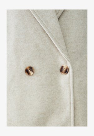 Divkrāsu mētelis gaiši bēšā vilnā, ar diviem brūniem, apaļiem pogām un gludu, teksturētu audumu ar smalku rakstu.