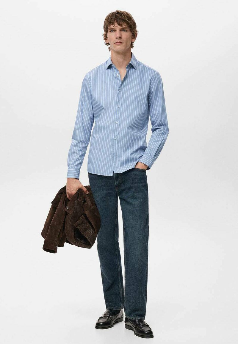 Hellblau gestreiftes Hemd mit Knöpfen, dunkelblaue Jeans und braune Wildlederjacke. Schwarze Schuhe. Schlichtes Design mit vertikalen Streifen und Hemdkragen.