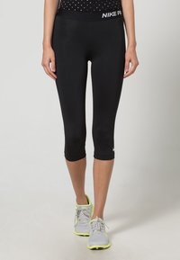 Mustat urheilulegginsit, joissa on tiukka malli, lyhennetty pituus ja suloinen elastinen vyötärö, jossa on "NIKE PRO" -brändäys.