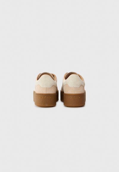 Sneakers met een bovenwerk van tan en roomkleurig suède, een bruine rubberen zool en een gestructureerde achterkant; met branding op de hak en een afgeronde vorm.