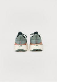 Scarpe sportive verdi e grigie con una tomaia testurizzata, tacco arrotondato e accenti corallo a contrasto. Presentano l'etichetta 'Soft Ride' sulla suola.