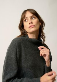 Czarny szary, dziany sweter z wysokim ściągaczem i szerokimi rękawami. Miękka tekstura, luźny krój oraz subtelne detale wokół krawędzi.