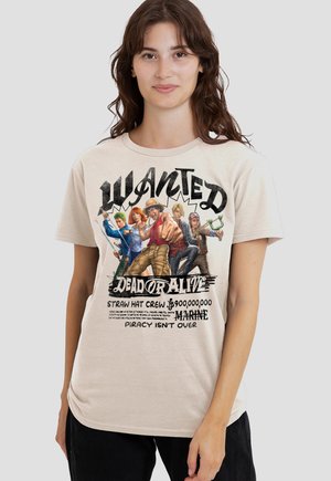 Young woman wearing beige t-shirt with colorful pirate crew characters and bold text "WANTED DEAD OR ALIVE STRAW HAT CREW" on front.
