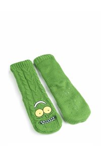 Grüne gestrickte Socken mit Zopfmuster und einem Cartoon-Gesicht mit großen Augen und einem breiten, zahnigen Grinsen. Rippbündchen am oberen Rand.