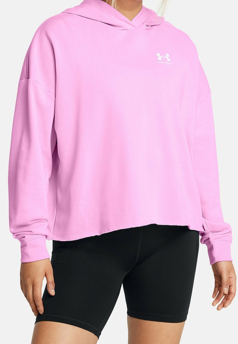 Sweat à capuche rose avec une coupe décontractée, des poignets côtelés et le logo Under Armour sur le côté gauche de la poitrine ; associé à un short noir taille haute.