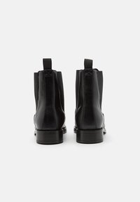 Schwarze Chelsea-Stiefel aus Leder mit elastischen Seitenteilen, rundem Zehenbereich und niedrigem gestapeltem Absatz. Verfügen über Schlaufen an der Rückseite für einfaches An- und Ausziehen.