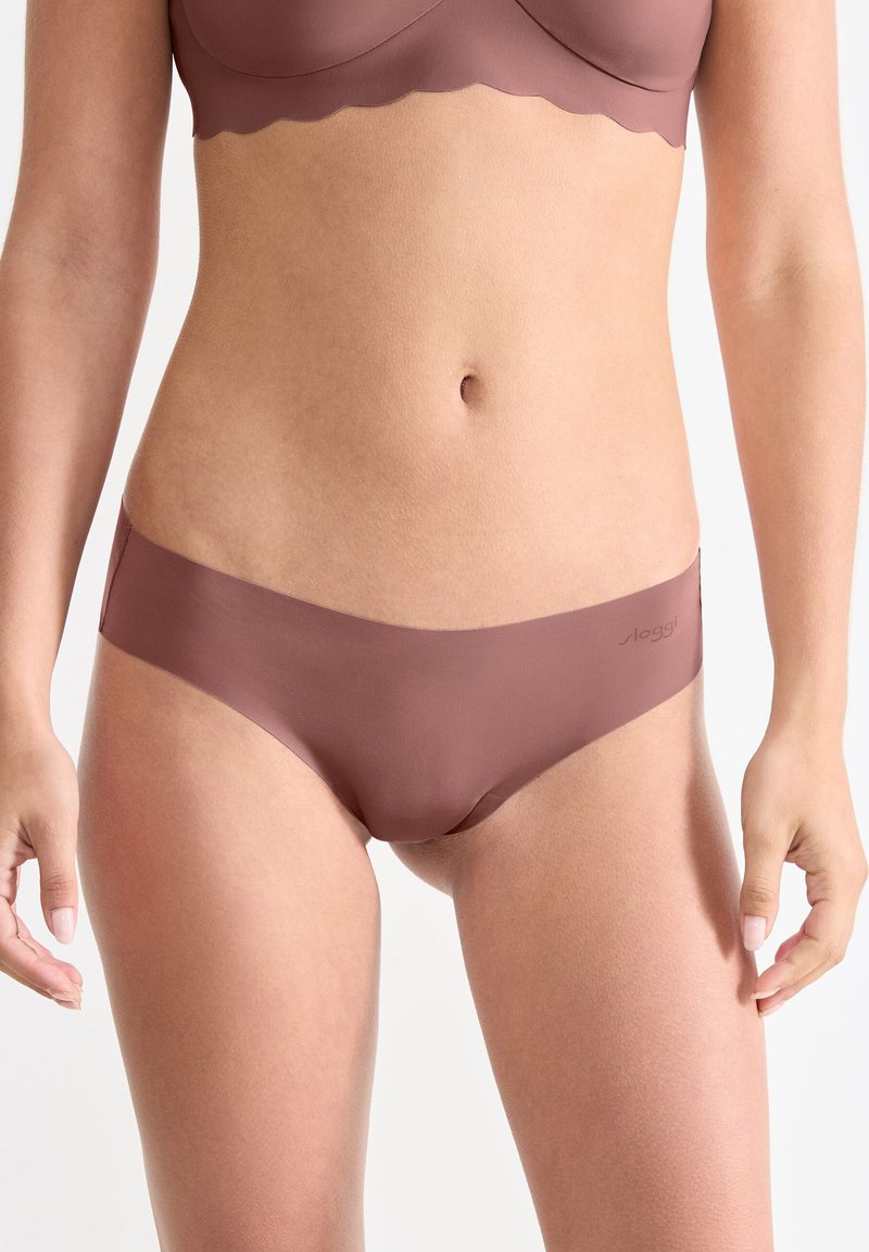 Sous-vêtements hipster de couleur brun clair, sans couture, avec une texture lisse, dotés d'une fine taille et d'un petit logo sur le côté.