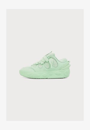 Lichtgroene lage sneaker met dikke zool, afgeronde veters en een gevoerde kraag, getoond van opzij op een witte achtergrond.