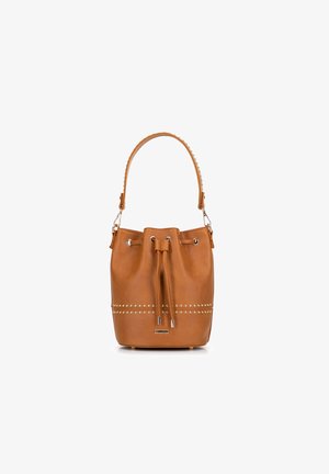 Sac seau en cuir tan avec une fermeture à cordon, accents cloutés autour de la base et une surface lisse et texturée.