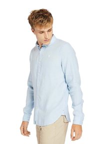 Camicia a manica lunga di lino azzurro chiaro, con colletto a bottoni, bottoni frontali e un piccolo logo sul petto.
