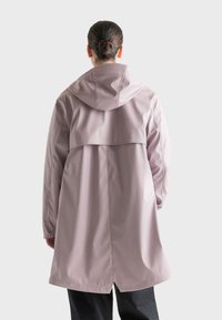 Svetloružový nepremokavý kabát s kapucňou, s vrstveným dizajnom na chrbte, dlhými rukávmi a rovnými líniami. Hladká textúra, minimálne švy.
