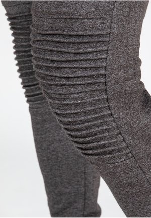 Graue, schmal geschnittene Hosen aus weichem Stoff mit vertikalen Rippdetails an den Seiten, die eine strukturierte Optik verleihen.