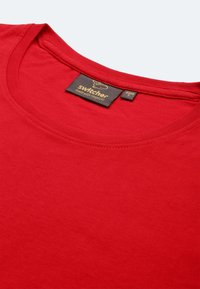 T-shirt in cotone rosso con scollatura rotonda e un'etichetta con il marchio "Switcher". Tessuto liscio e design semplice a tinta unita.