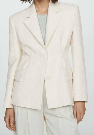 Witte gestructureerde blazer met scherpe revers, enkele knoopsluiting en twee voorzakken. Draag het over een lichtgrijze top en crèmekleurige broek.