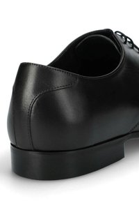 Czarna skórzana sznurowana półbut z gładkim wykończeniem, zaokrąglonym obcasem i minimalistycznym designem z subtelnym detalem szwu. Zapięcie na sznurowadła z przodu.