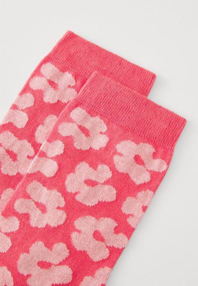 Rosa bomullssockor med ett blommigt mönster i ljusare nyanser. Har en ribbad mudd och en mjuk, texturerad finish.