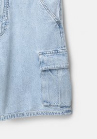Svetlo modri denim kos z stranskim žepom in vidnimi šivi. Tekstura blaga je mehka, z rahlo zbledelim videzom.