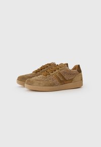 Brown sneakers featuring a textured fabric upper with suede accents, round toe, and rubber outsole. Laces and contrasting stripes detail the design.