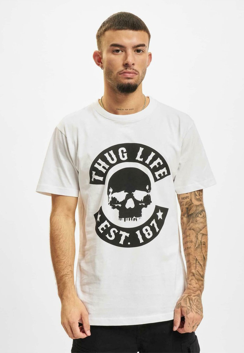 Balta kokvilnas T-krekls ar lielu melnu galvaskausa grafiku, kurā ir teksts "THUG LIFE" un "EST. 187" apļa dizainā. Īsas piedurknes, apaļa kakla izgriezums.