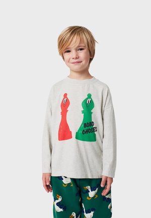 Langarm-Graues T-Shirt mit roten und grünen - Cartoon-Schachfiguren. Kombiniert mit grünen Hosen, die ein Entenmuster zeigen. Aus weicher Baumwolle.