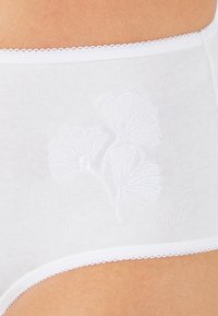 Witte katoenen slips met delicate scalloped kantafwerking. Bevat subtiele bloemengestikte motieven aan de voorkant. Zachte textuur en ontwerp met volledige dekking.