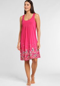 Sleeveless pink dress in soft fabric with a pleated bodice, featuring a floral pattern in blue, yellow, and white at the hem.