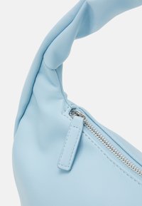 Ljusblå läderväska med en tvinnad rem, med dragkedja och detaljer i silver. Slät yta, minimalistisk design.