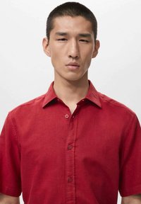 Rotes Hemd mit kurzen Ärmeln und Knopfleiste aus leichtem Stoff, mit einem Kragen und feiner Textur.